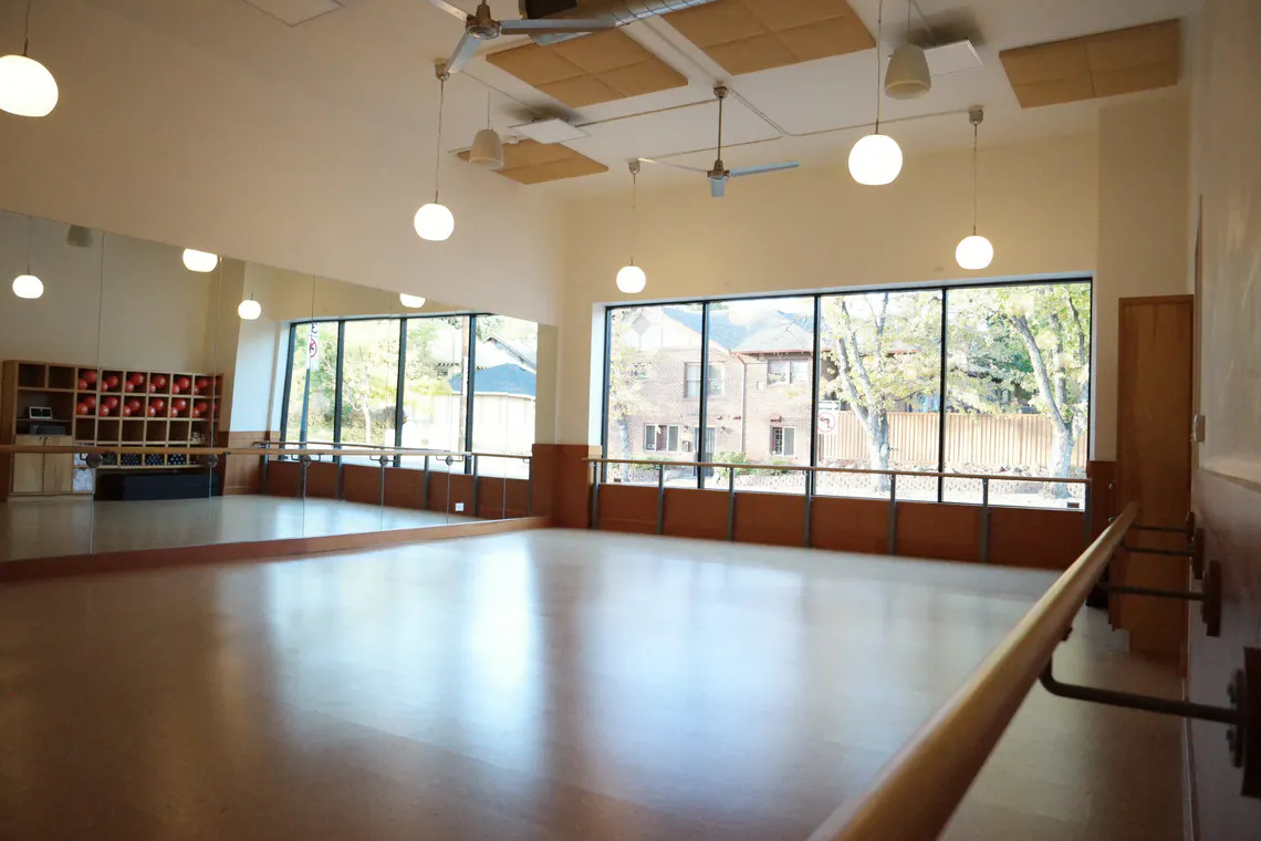 inside of a barre3 studio showing cork floor, open wall of windows, and barre rails