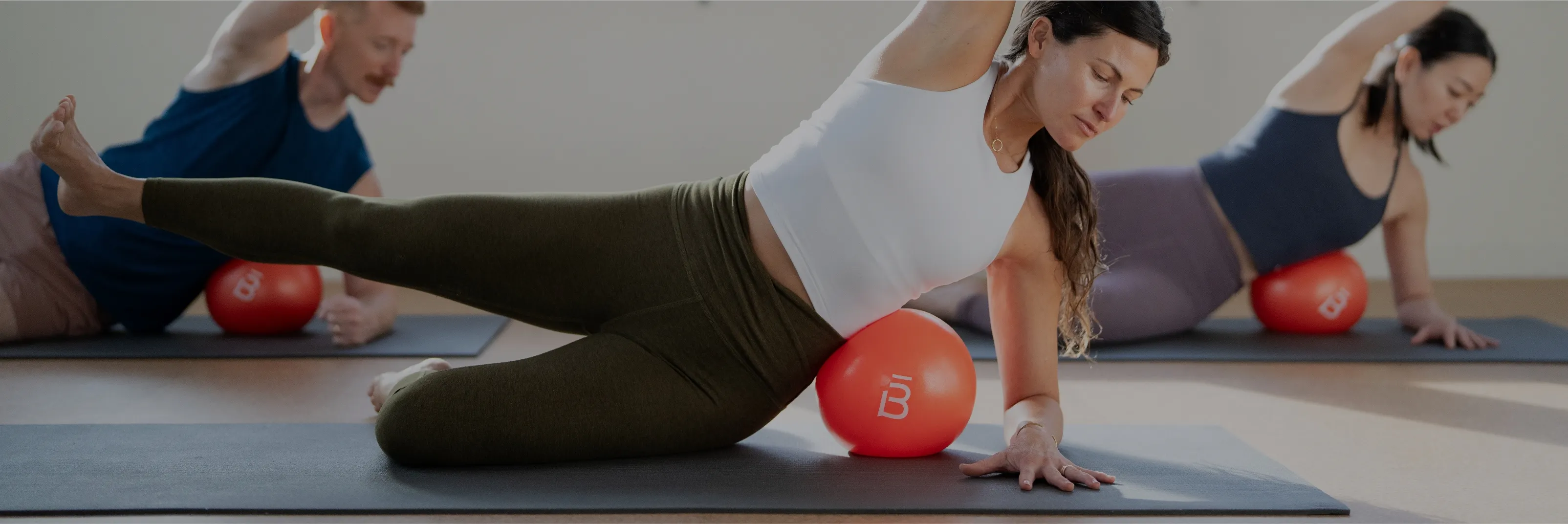 clients in a side plank with a core ball under their ribs