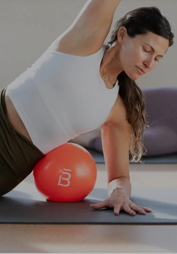 clients in a side plank with a core ball under their ribs