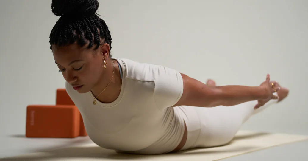 woman on her stomach with her arms and legs lifted behind her