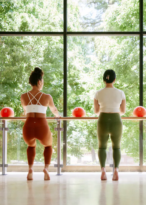 two women at a ballet barre up on their toes
