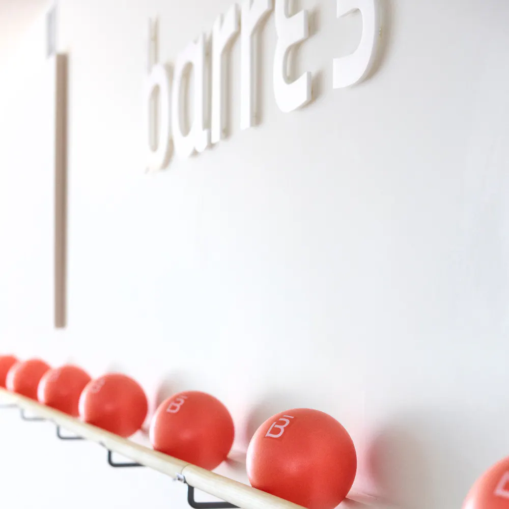 orange squishy balls on a barre rail underneath the barre3 logo