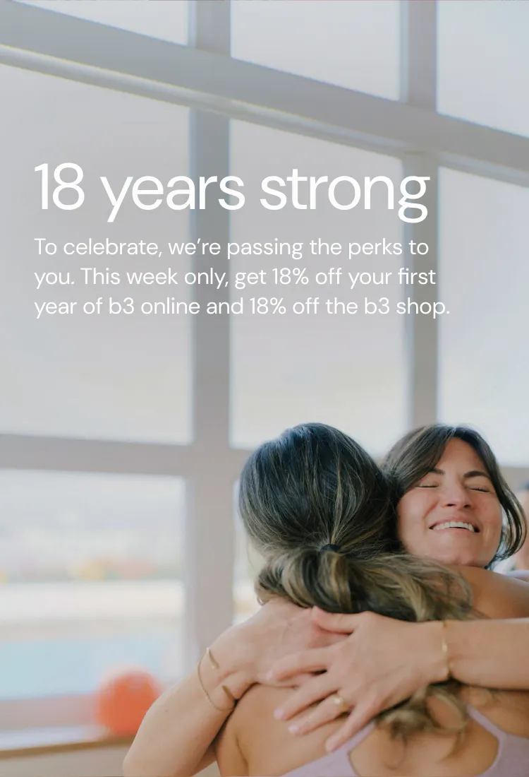 two women hugging in a barre studio with an orange barre3 core ball behind them
