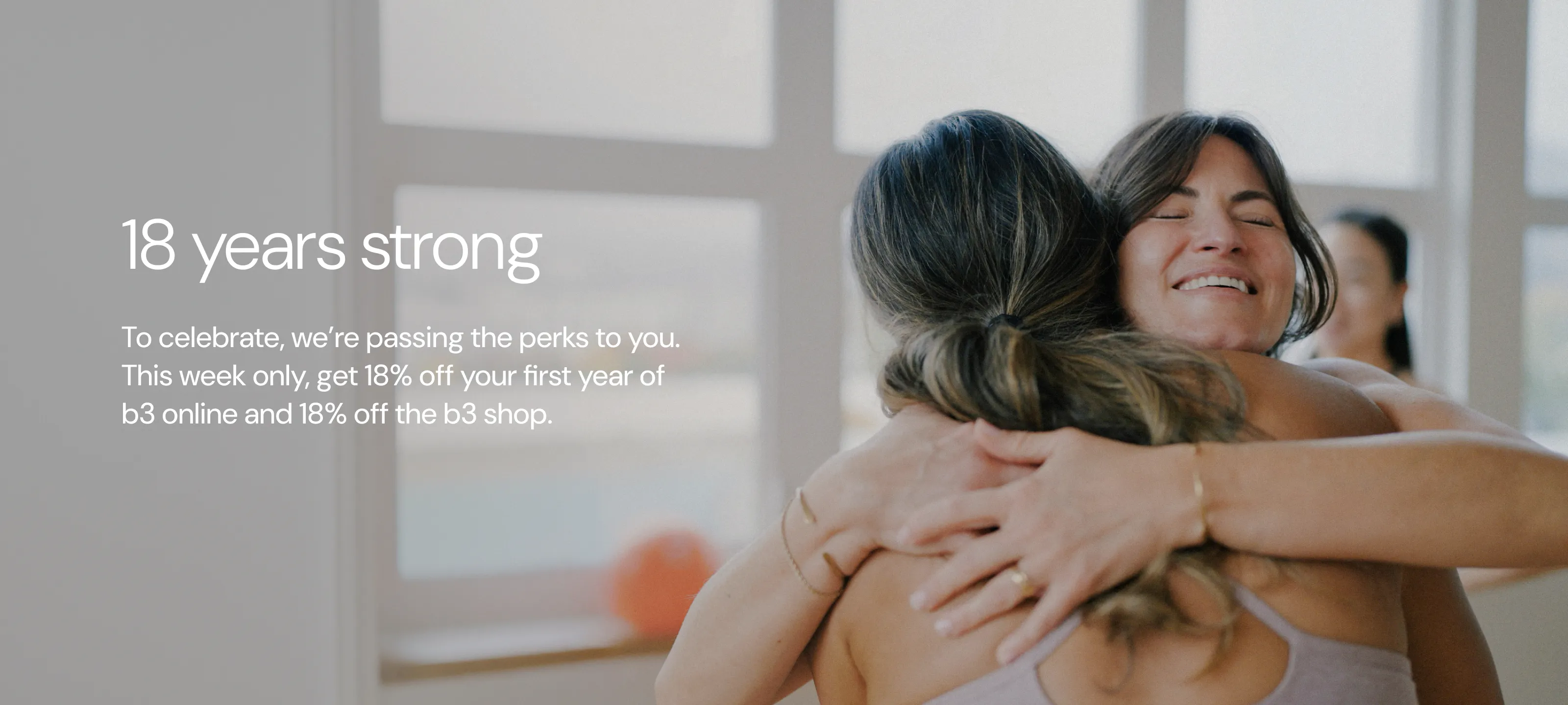 two women hugging in a barre studio with an orange barre3 core ball behind them